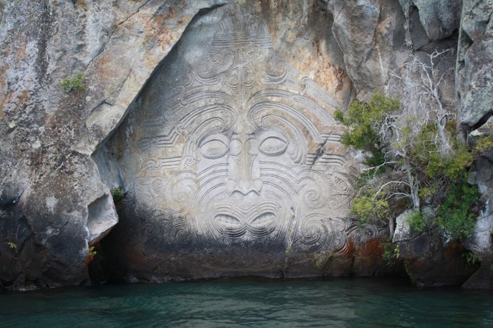 Maori - body of water between gray rock formation during daytime