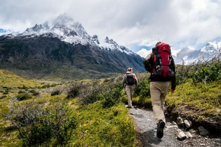 Hiking - two person walking towards mountain covered with snow