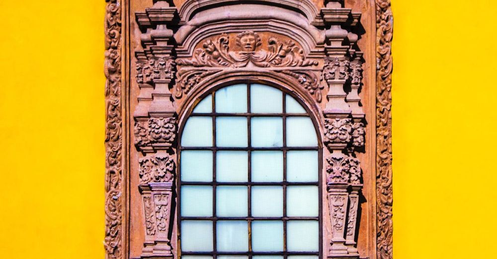 Colonial History - Exterior detail of ancient Capilla de Aranzazu chapel with carved ornamental window on bright yellow wall in Spanish colonial style located in San Luis Potosi